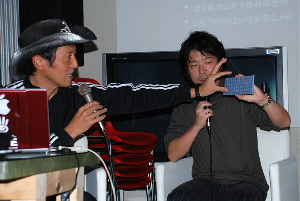 二つ折りキーボードのモックについて解説中のキングジム立石氏（右）。左はビデオジャーナリストの神田敏晶氏。