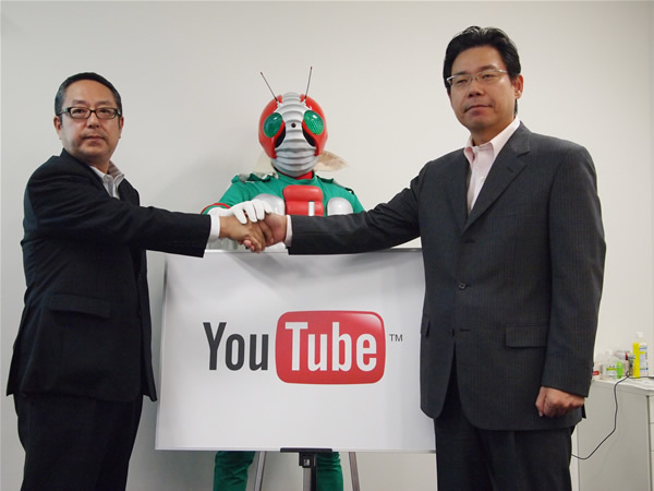 発表にあたり協力体制を誓った、YouTubeコンテンツパートナーシップ統括部長水野有平氏（右）、東映株式会社折坂哲夫氏（左）、仮面ライダーV3（中央）