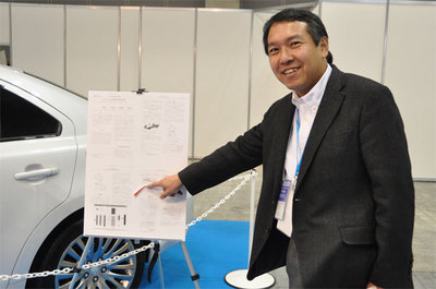 展示車の横に提示されていたスズキ自動車の技報にもTOPPERS OSの紹介が。指さしで説明しているのはTOPPERSプロジェクト会長の高田広章 名古屋大学教授。