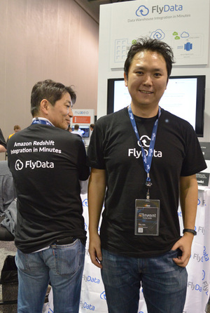 会場のFlyDataブース前でインタビューを受ける藤川幸一氏（右）、同社のロゴ入りTシャツにはRedshiftのロゴも。これを許されるのは特別なパートナーだけとのこと