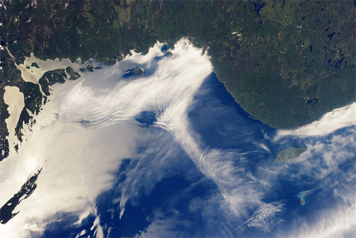 左下の雲に囲まれた緑の領域がアイル・ロイヤルの先端部分。この周辺から右側に見えるミシピコテン島（Michipicoten Island）のあたりまで、湖面のさざなみがはっきり確認できる鏡面反射が起こっている。重力波による雲のうねりとさざなみの向きが同じことから、2つの現象ともに、陸からの風に影響されていることがわかる。