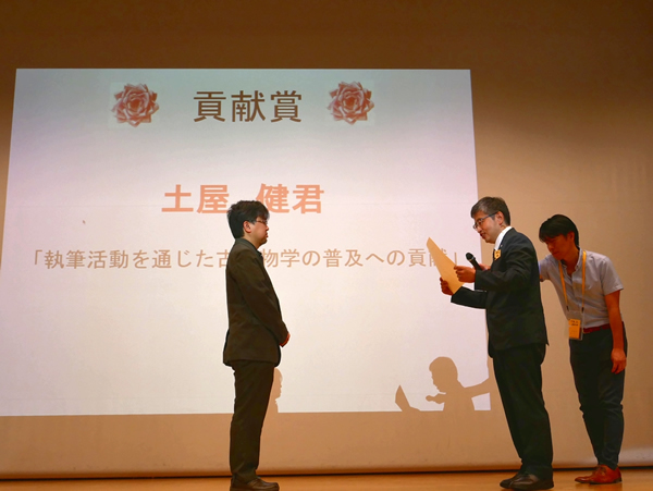 真鍋真日本古生物学会会長より、土屋健氏に表彰状が授与される